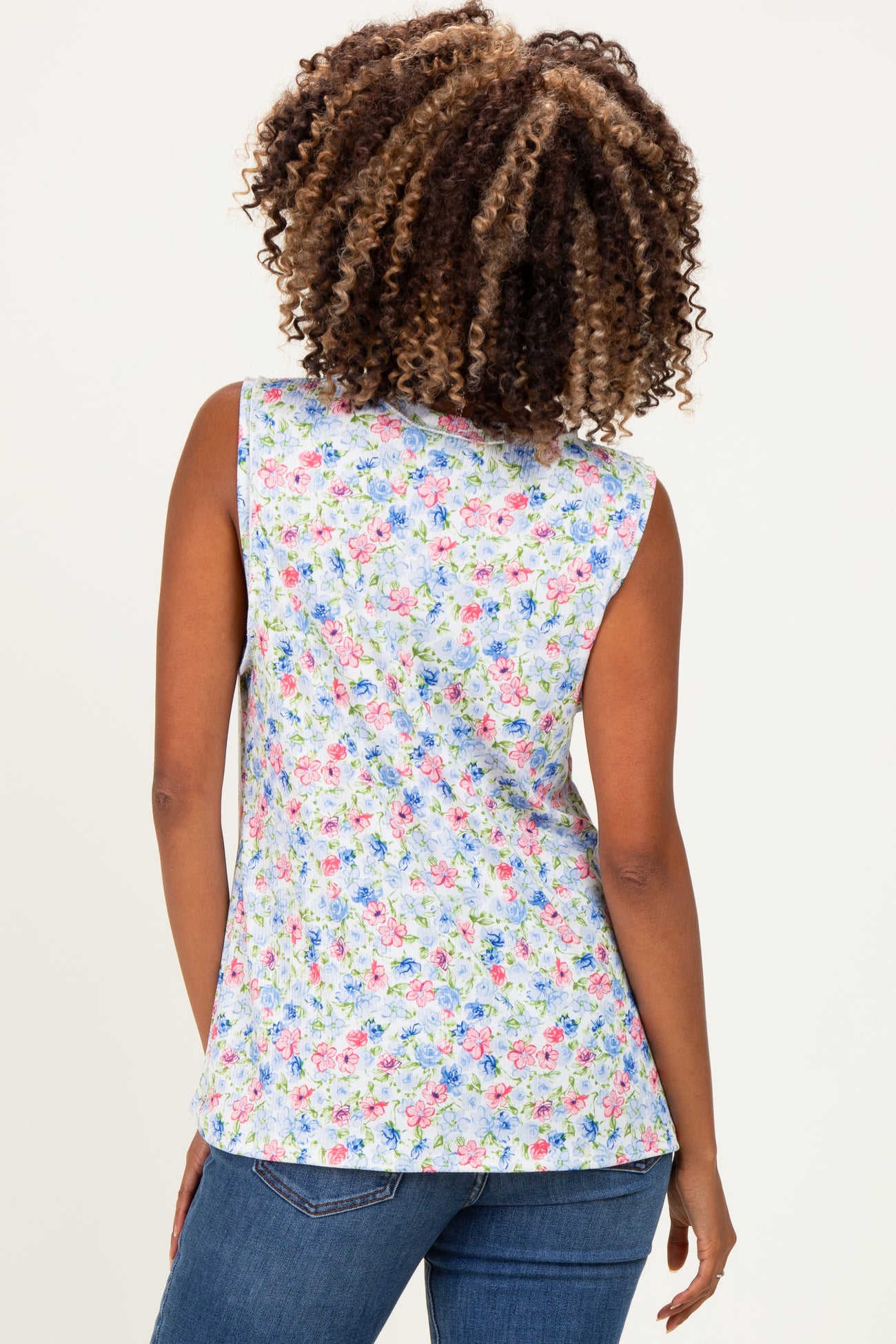 woman wearing a floral print sleeveless maternity top, showing the back view with a colorful pattern and light blue background