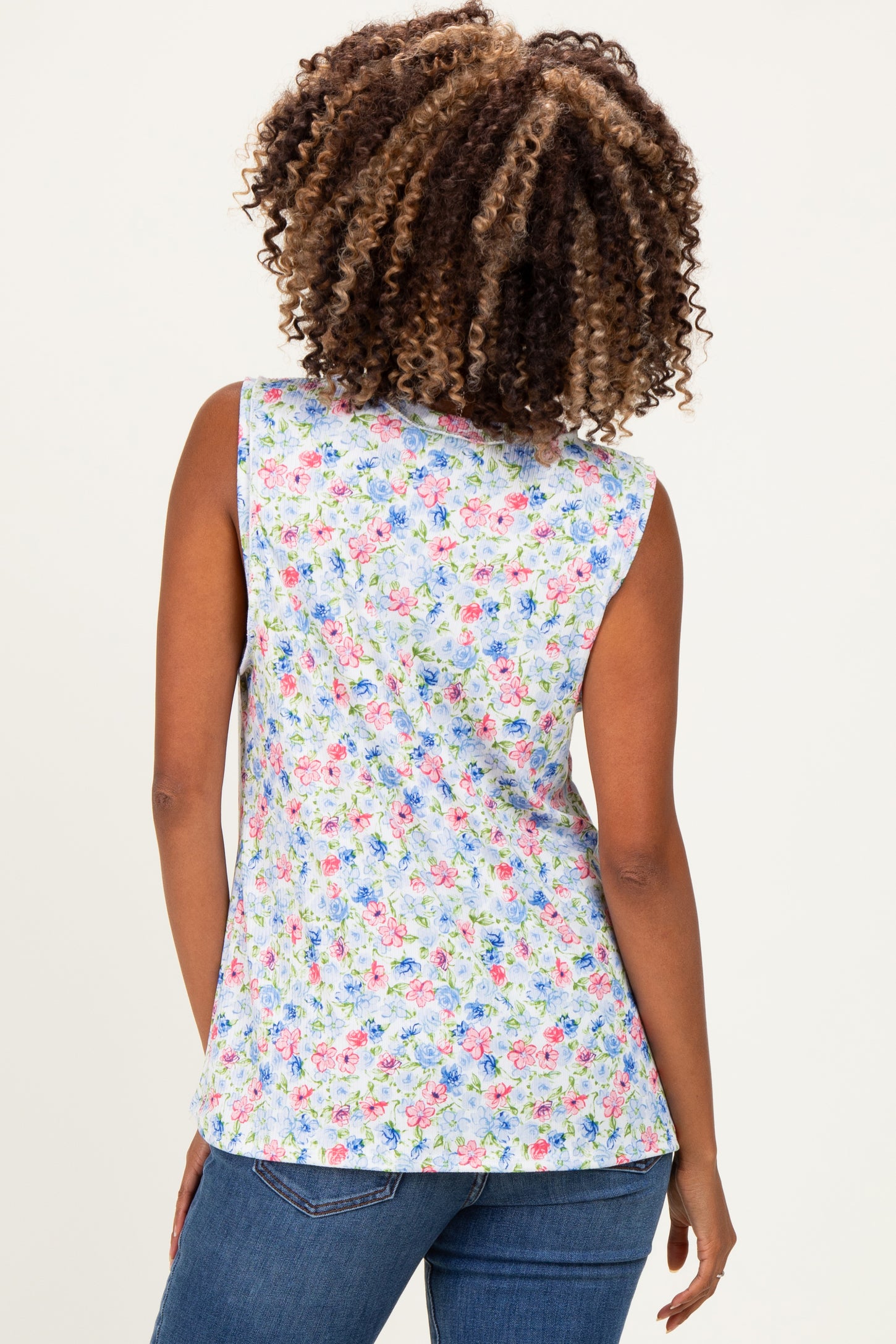 woman wearing a floral print sleeveless maternity top, showing the back view with a colorful pattern and light blue background