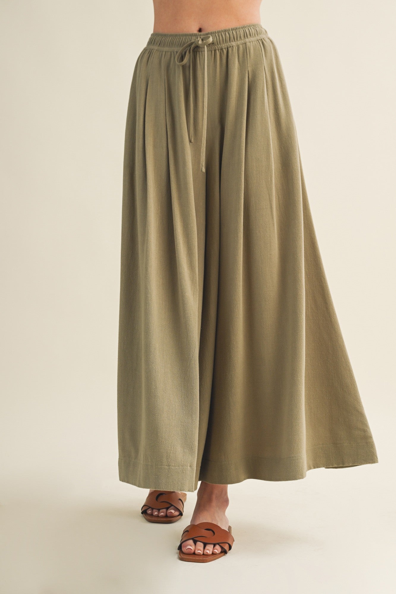 woman wearing olive green wide-leg pants with an elastic waistband and drawstring detail