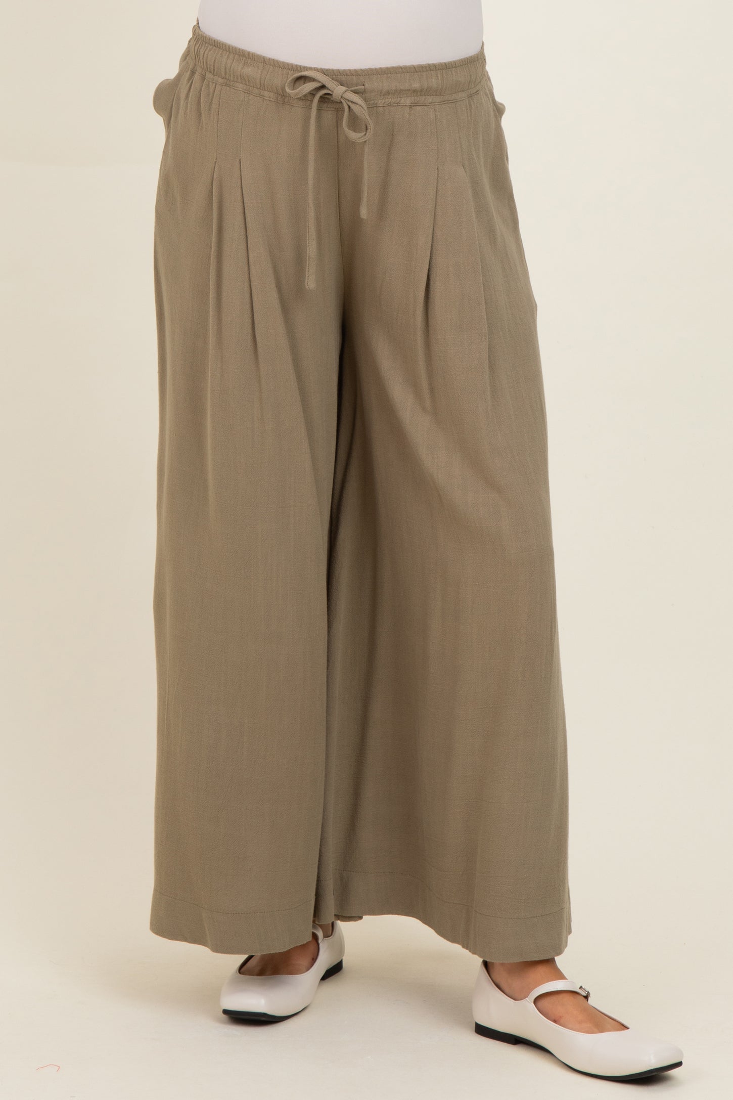 woman wearing olive green maternity wide-leg pants with a drawstring waist and pleated details