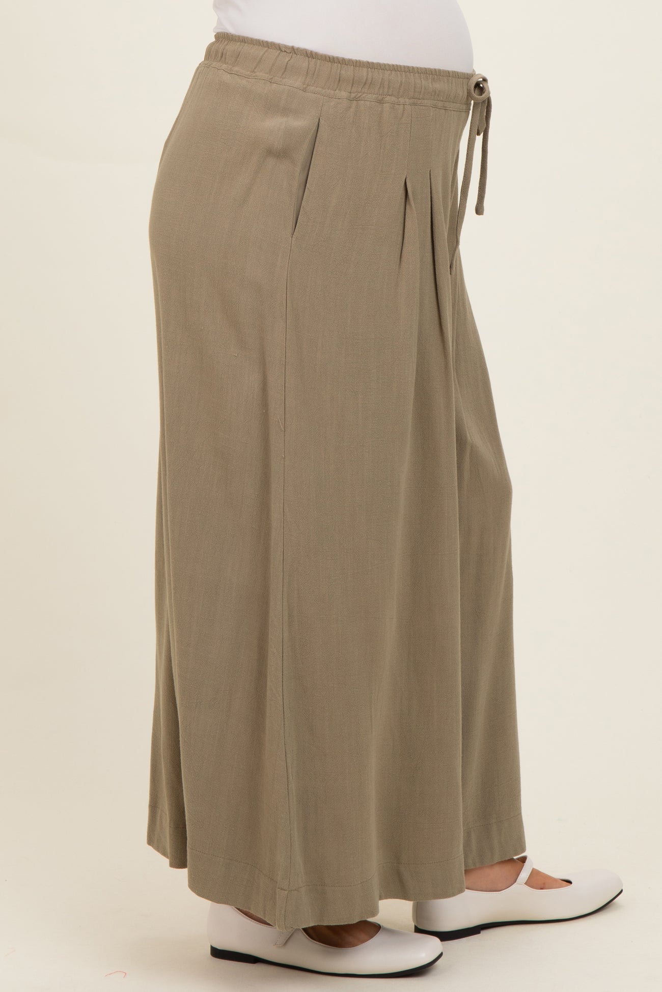 maternity wear in khaki wide leg pants with an elastic waistband and drawstring, featuring pleats and a visible baby bump