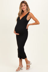 woman wearing a black ribbed maternity dress with a deep v-neck and side buttons, showcasing her baby bump