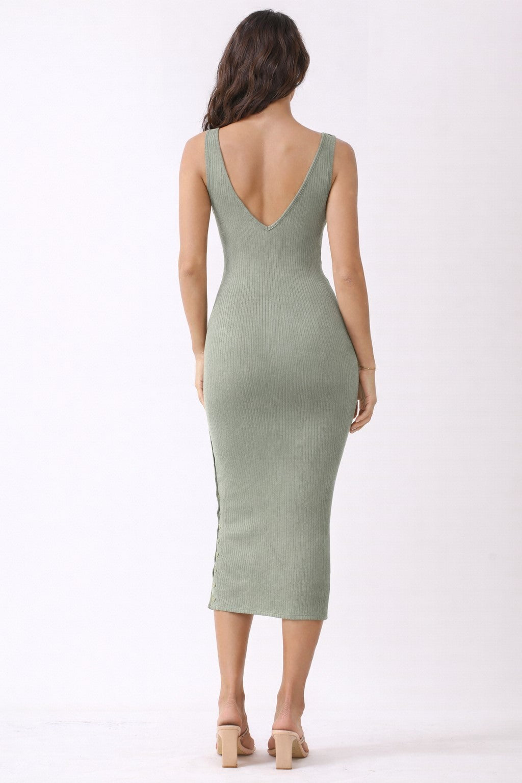 woman wearing a ribbed olive green midi dress with a deep v-back and side slit, styled with open-toe heels