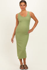 woman wearing a green ribbed maternity dress, showing her baby bump with a fitted silhouette