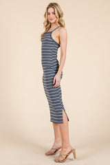 woman wearing a navy and white striped sleeveless midi dress with side slits and wearing beige heeled sandals