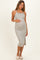 woman wearing a striped maternity midi dress with spaghetti straps and a side slit, gently cradling her baby bump