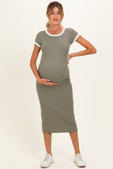 woman wearing a fitted olive green maternity dress with white trim and holding her baby bump