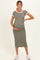 woman wearing a fitted olive green maternity dress with white trim and holding her baby bump