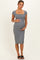 woman wearing a fitted gray maternity dress with short sleeves, holding her baby bump and standing straight