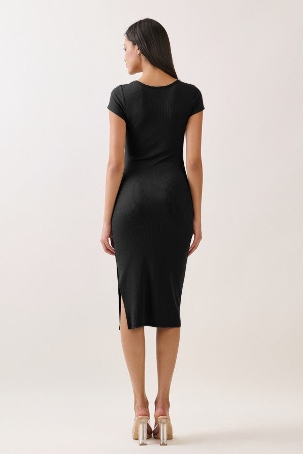 woman wearing a fitted black short sleeve dress with side slits and a midi length, standing with her back to the camera