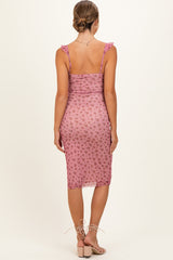 woman wearing a pink floral maternity dress with ruffle straps and midi length, showing off her baby bump