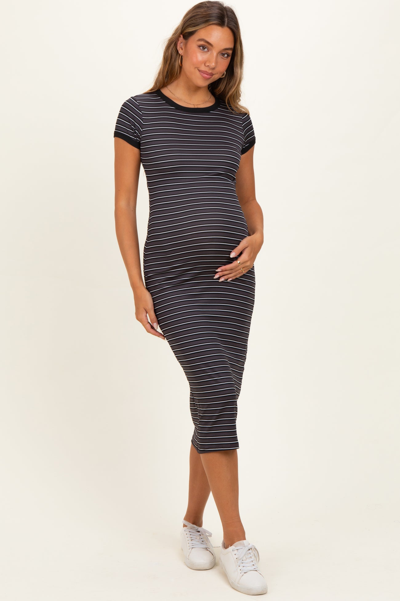 woman wearing a striped black and white maternity dress, showcasing her baby bump with short sleeves and a fitted style