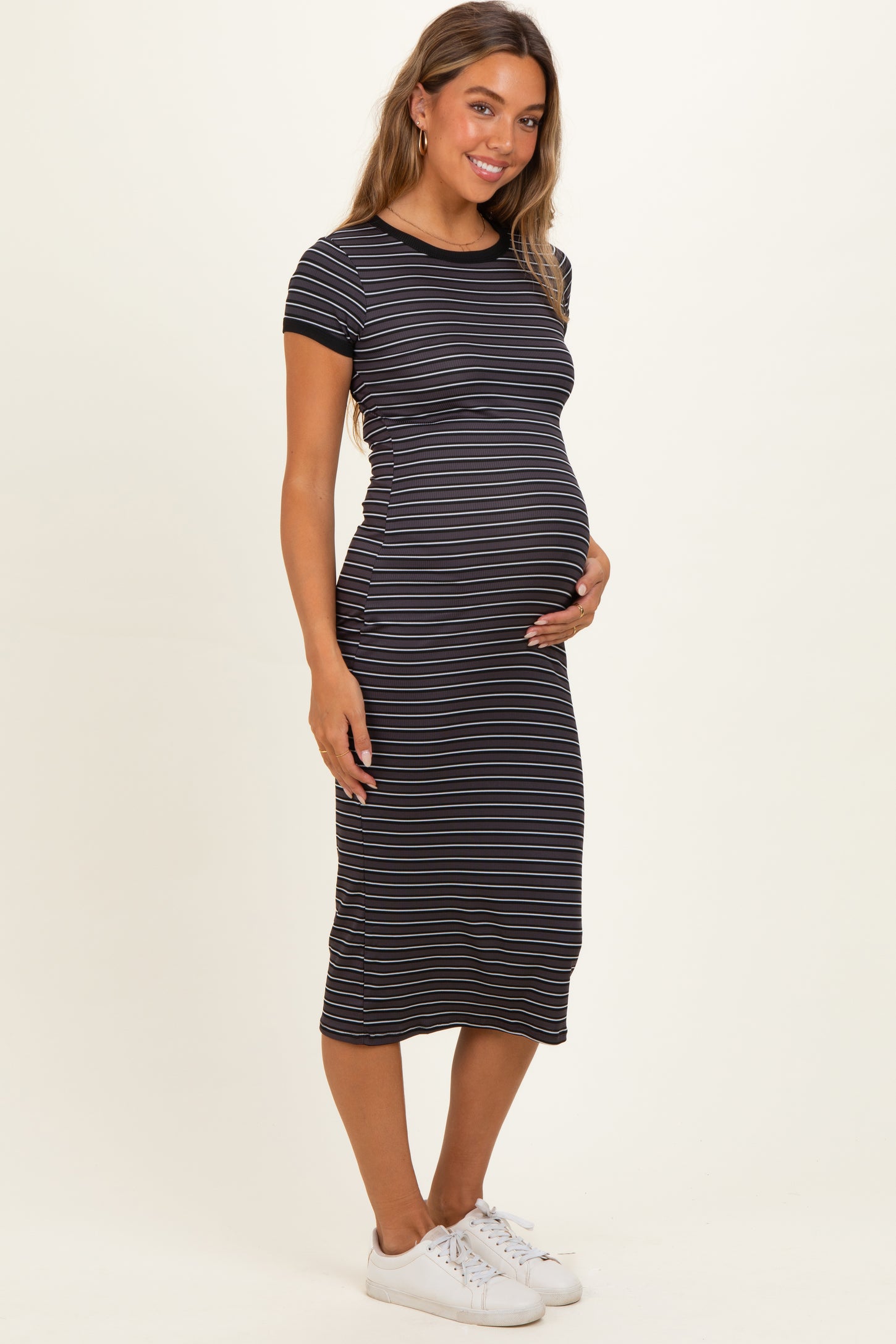 woman wearing a black and white striped maternity dress and holding her baby bump