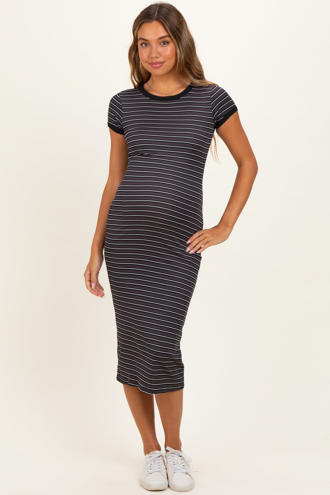 woman wearing a black and white striped maternity dress with short sleeves and a fitted silhouette, showcasing her baby bump