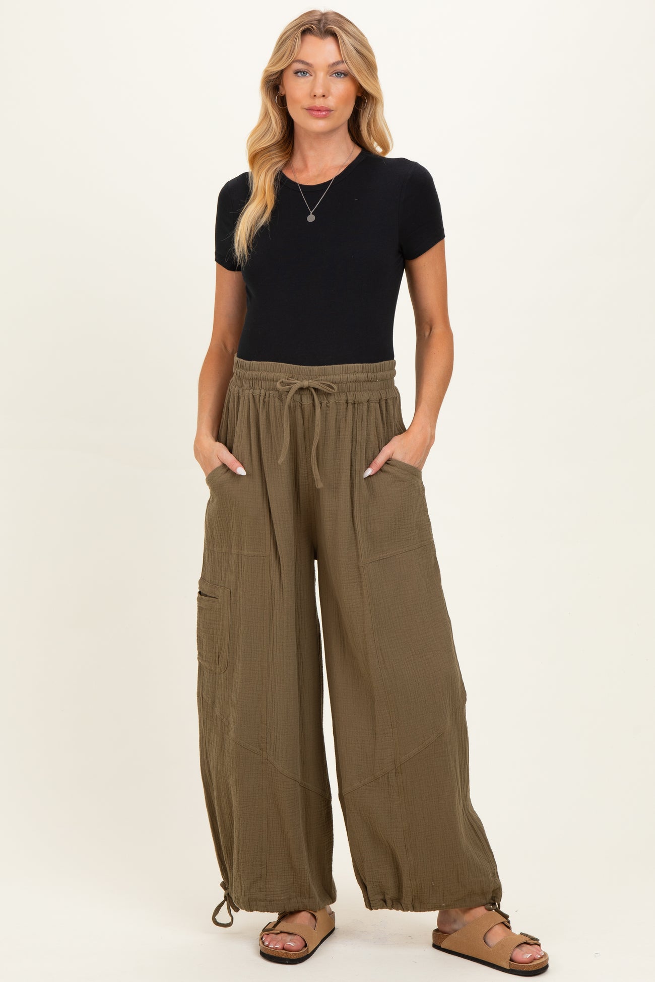 woman wearing a black short sleeve top and olive green wide leg maternity pants with drawstring and pockets