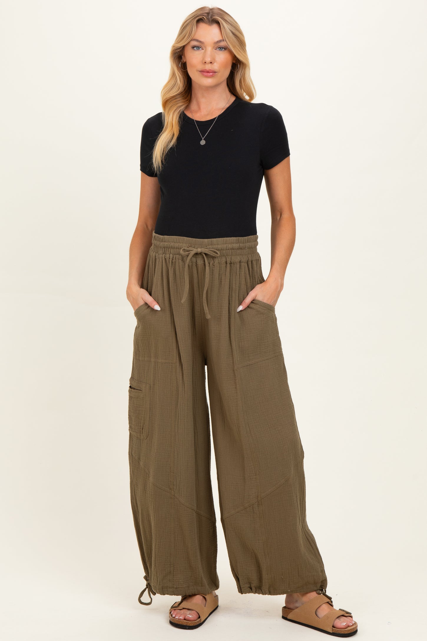 woman wearing a black short sleeve top and olive green wide leg maternity pants with drawstring and pockets