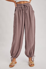 woman wearing loose-fitting mauve textured pants with drawstring waist and gathered cuffs