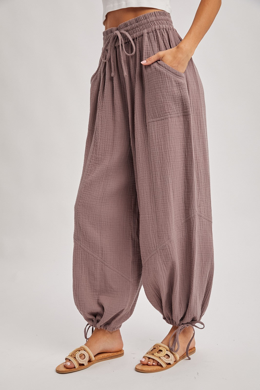 woman wearing loose-fitting mauve fabric lounge pants with elastic waistband and cinched ankles, styled with sandals