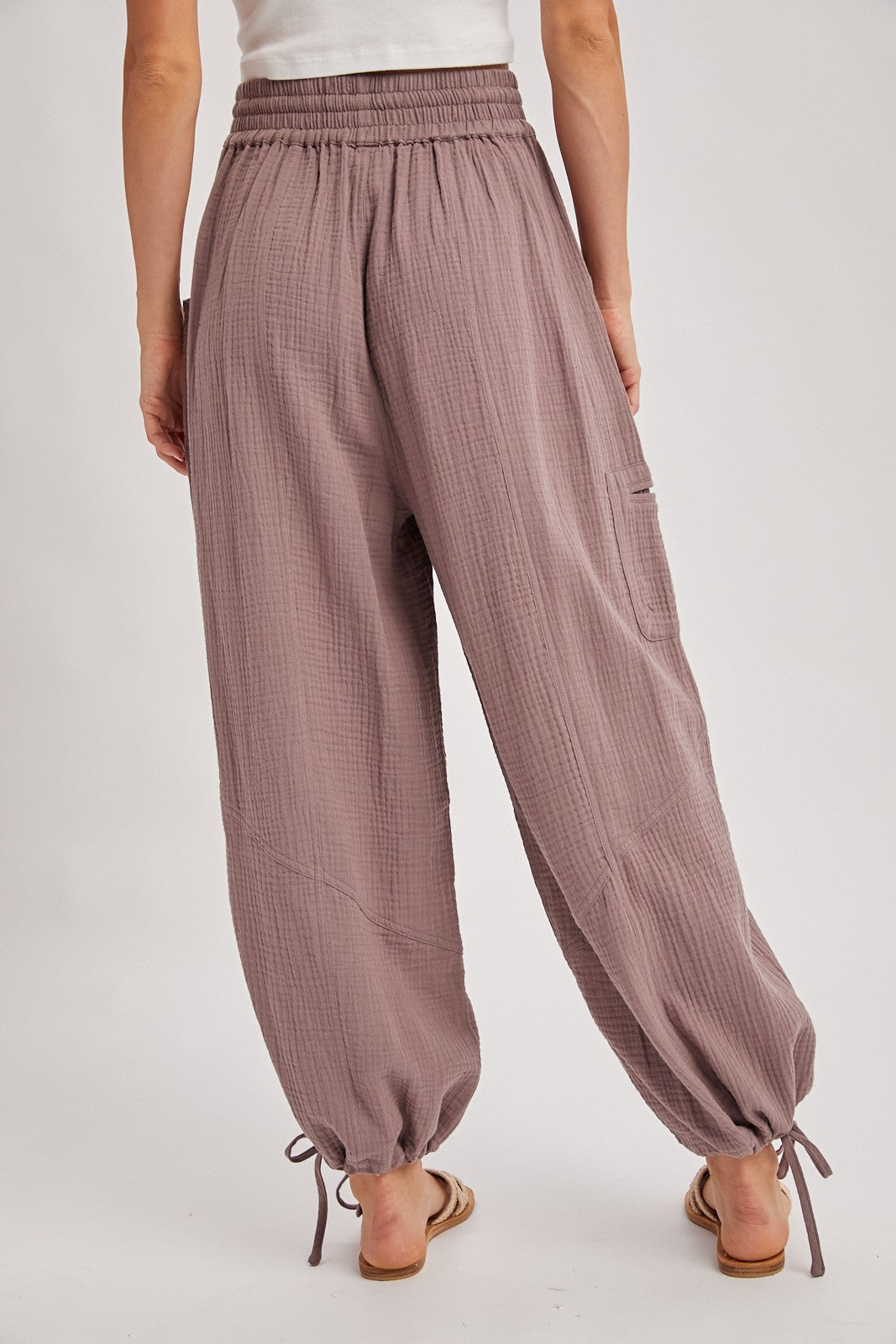 woman wearing light mauve loose-fitting jogger pants with elastic waistband and drawstring cuffs, viewed from behind