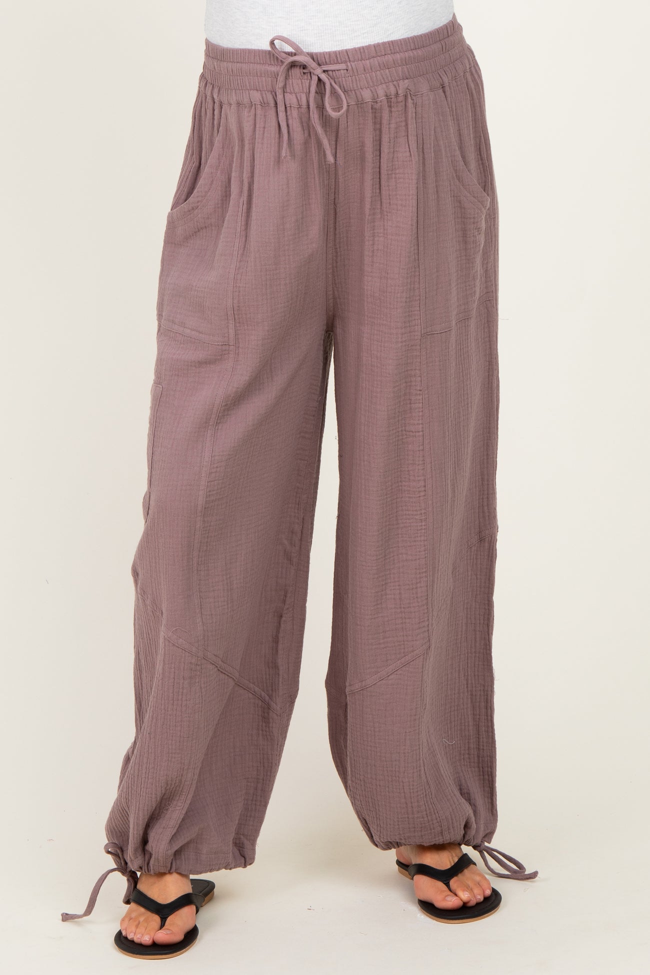 woman wearing mauve maternity pants with pockets and elastic drawstring waist, paired with black sandals