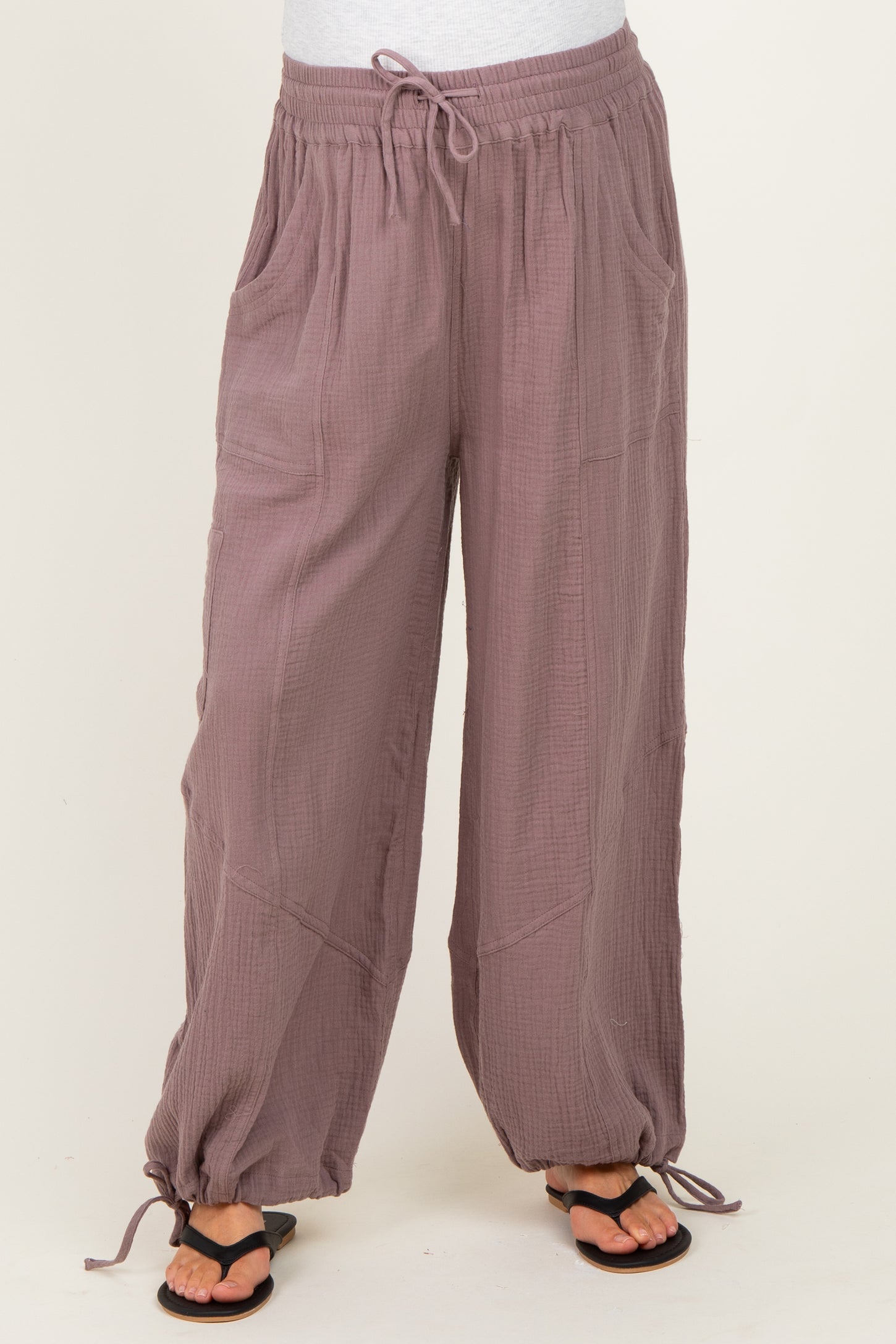 woman wearing mauve maternity pants with pockets and elastic drawstring waist, paired with black sandals
