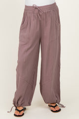 woman wearing mauve maternity pants with pockets and elastic drawstring waist, paired with black sandals