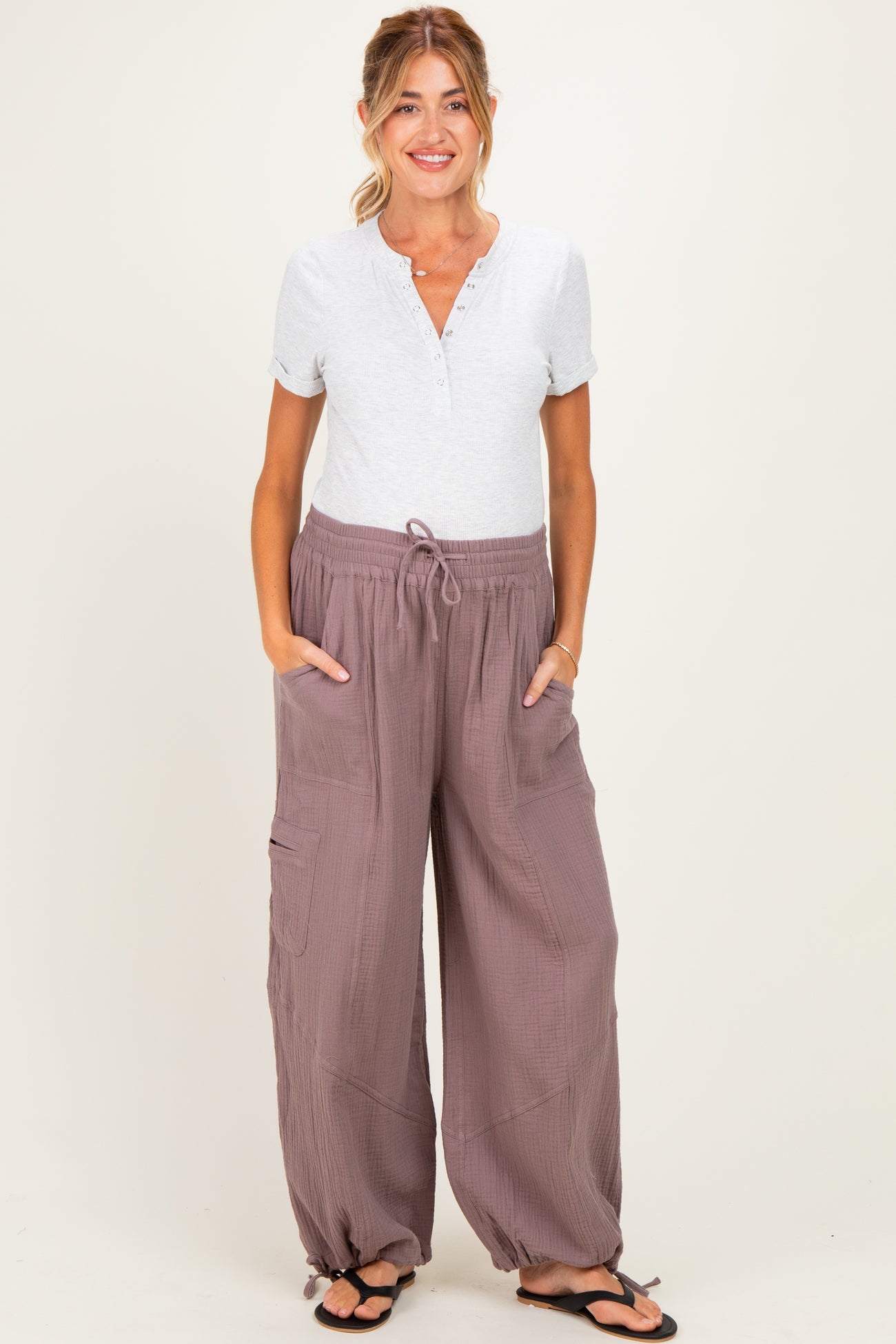 woman wearing a light grey maternity henley top and loose mauve maternity lounge pants with pockets