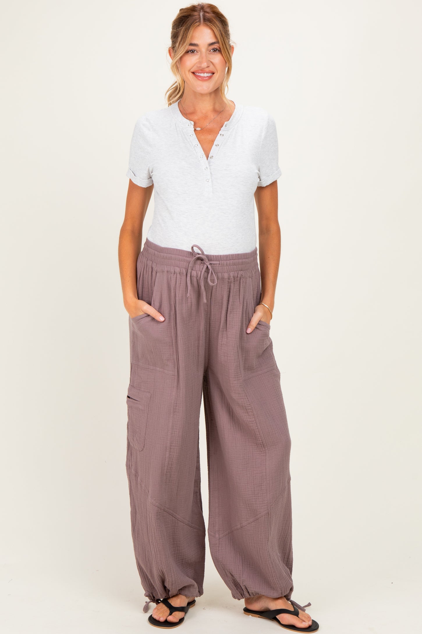 woman wearing a light grey maternity henley top and loose mauve maternity lounge pants with pockets