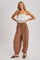 woman wearing a white smocked strapless top and brown loose fit drawstring pants