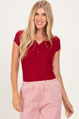 woman wearing a ruby red short sleeve henley top paired with striped shorts