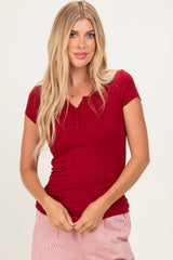 woman wearing a red short sleeve ribbed henley top with buttons, styled with striped pants