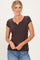 woman wearing a dark brown short sleeve henley top with buttons, smiling against a light background