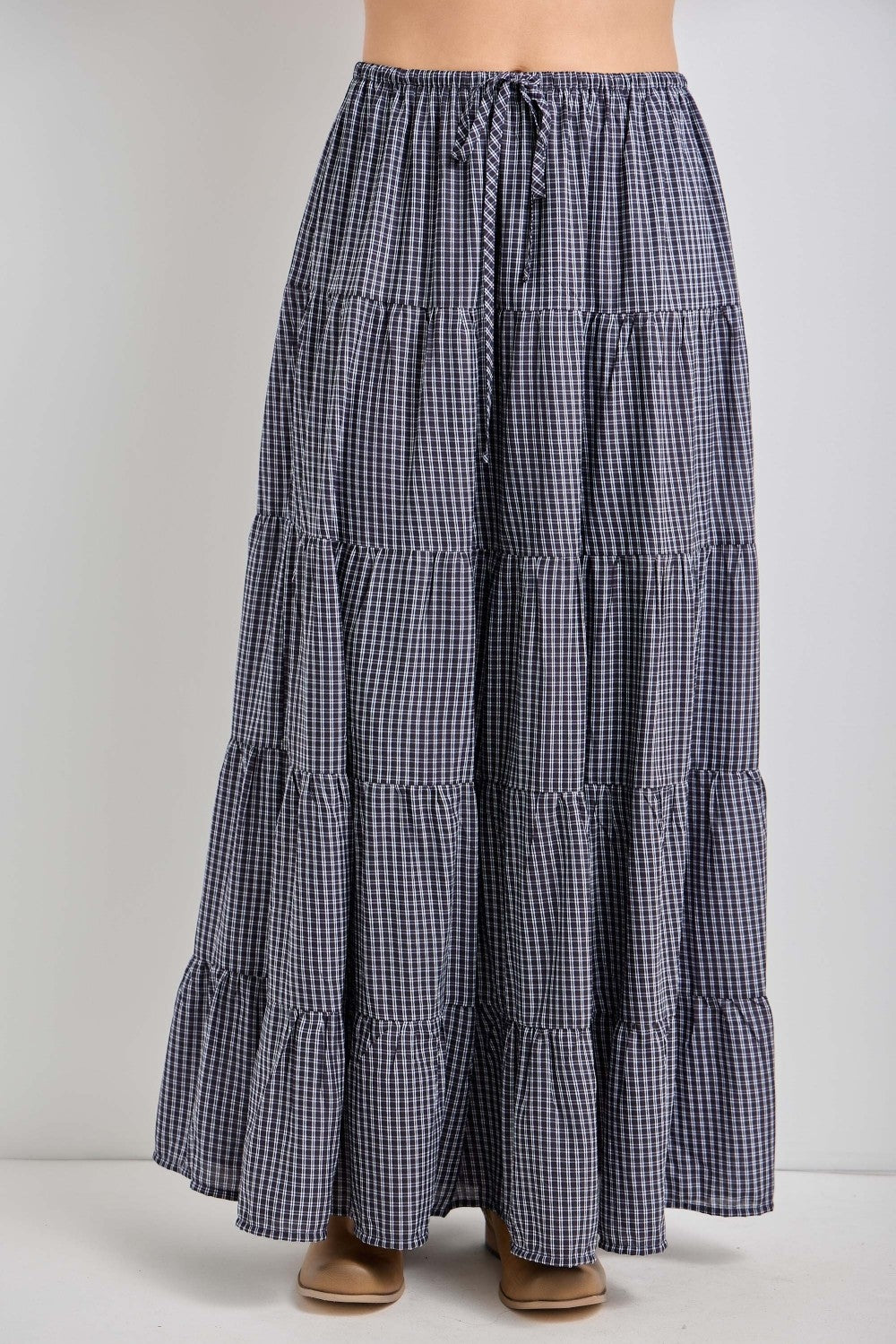 woman wearing a navy and white gingham tiered maxi skirt with a drawstring waist and flared hem