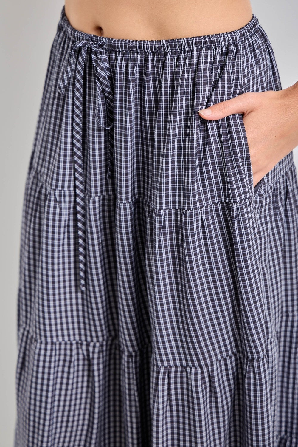 woman wearing a navy and white checkered tiered maxi skirt with an elastic waistband and pockets