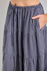 woman wearing a navy and white checkered tiered maxi skirt with an elastic waistband and pockets