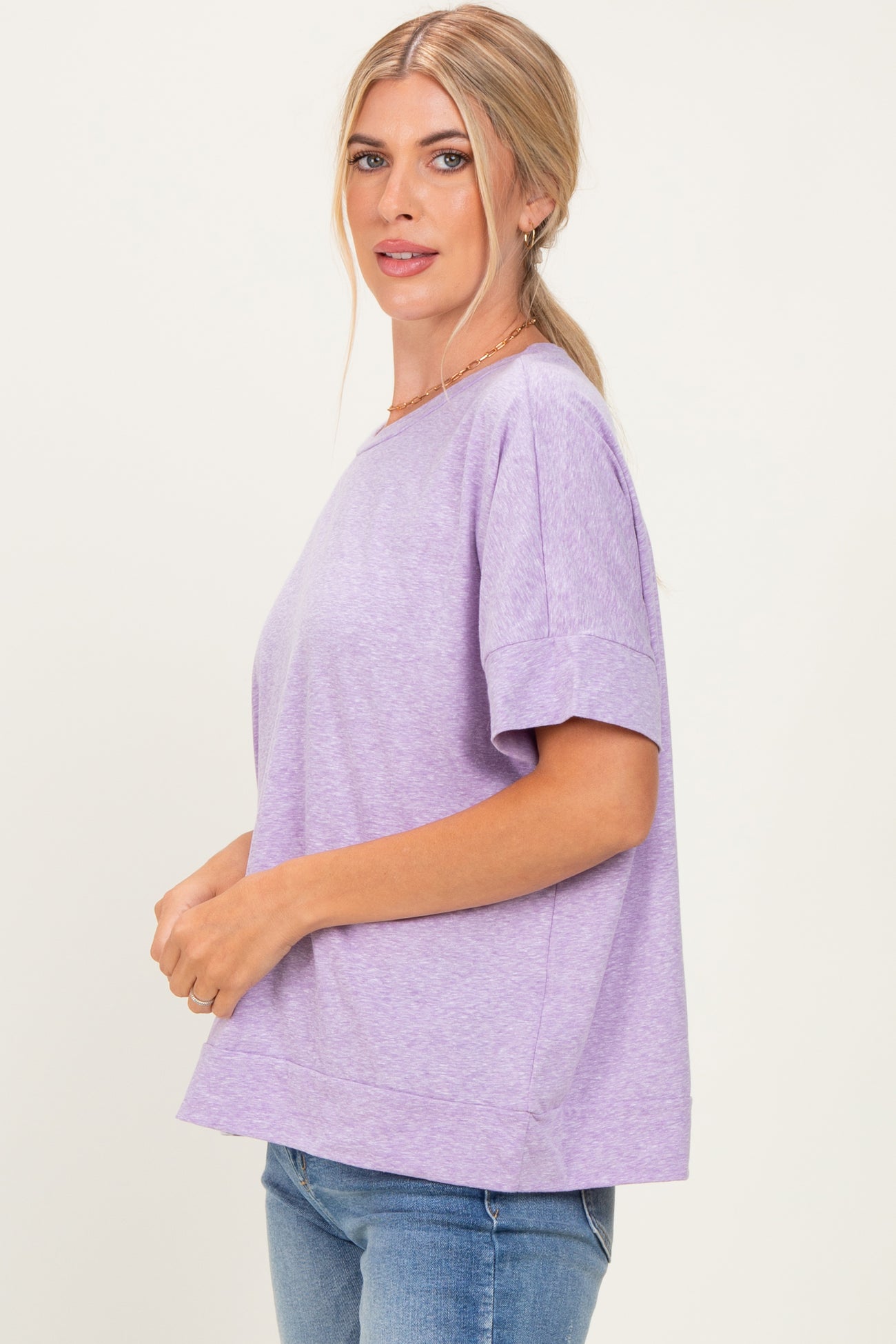 woman wearing a light purple short sleeve top with a relaxed fit and a round neckline, styled with jeans
