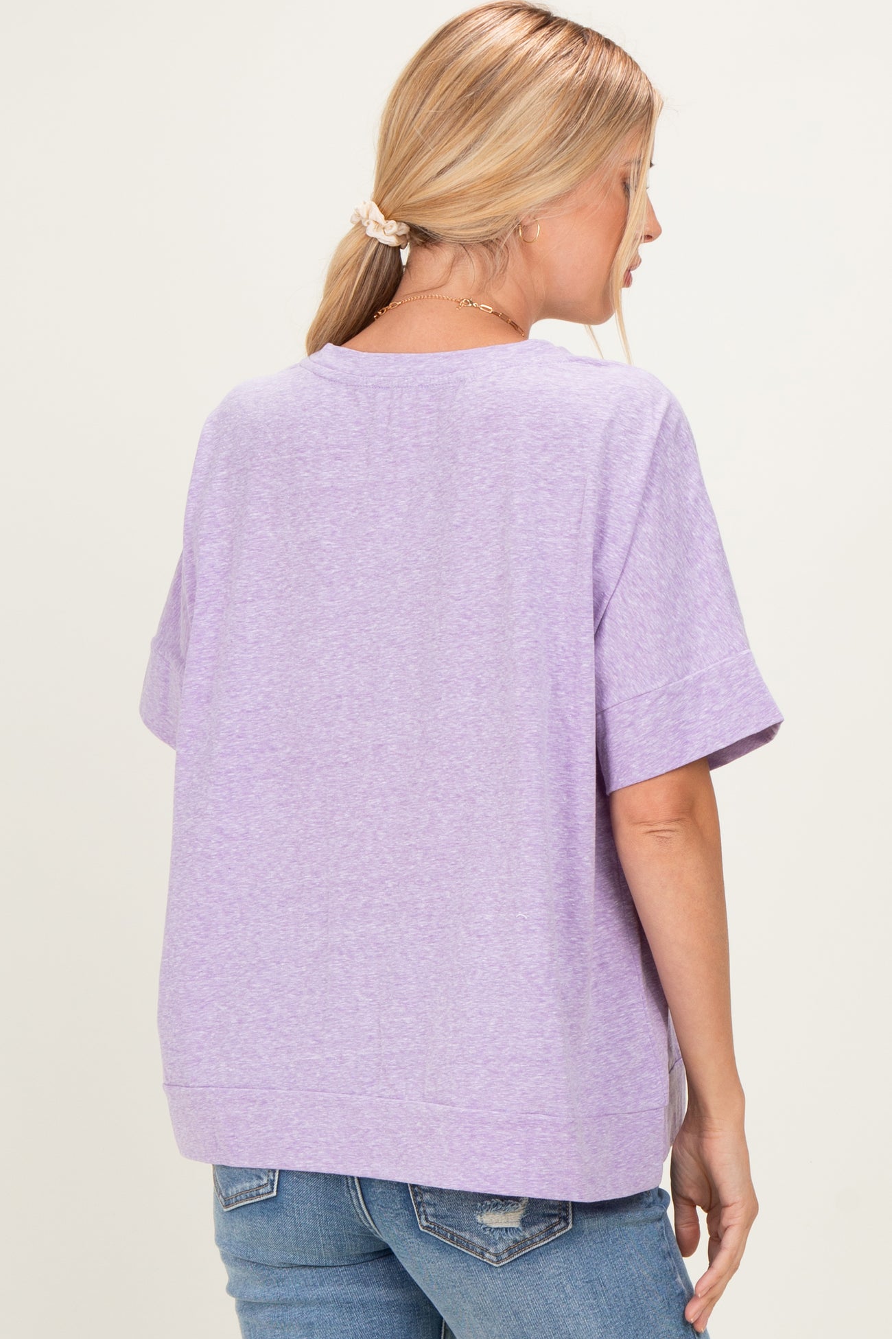 woman wearing a lavender loose fit short sleeve t-shirt from the back with a round neckline and casual style