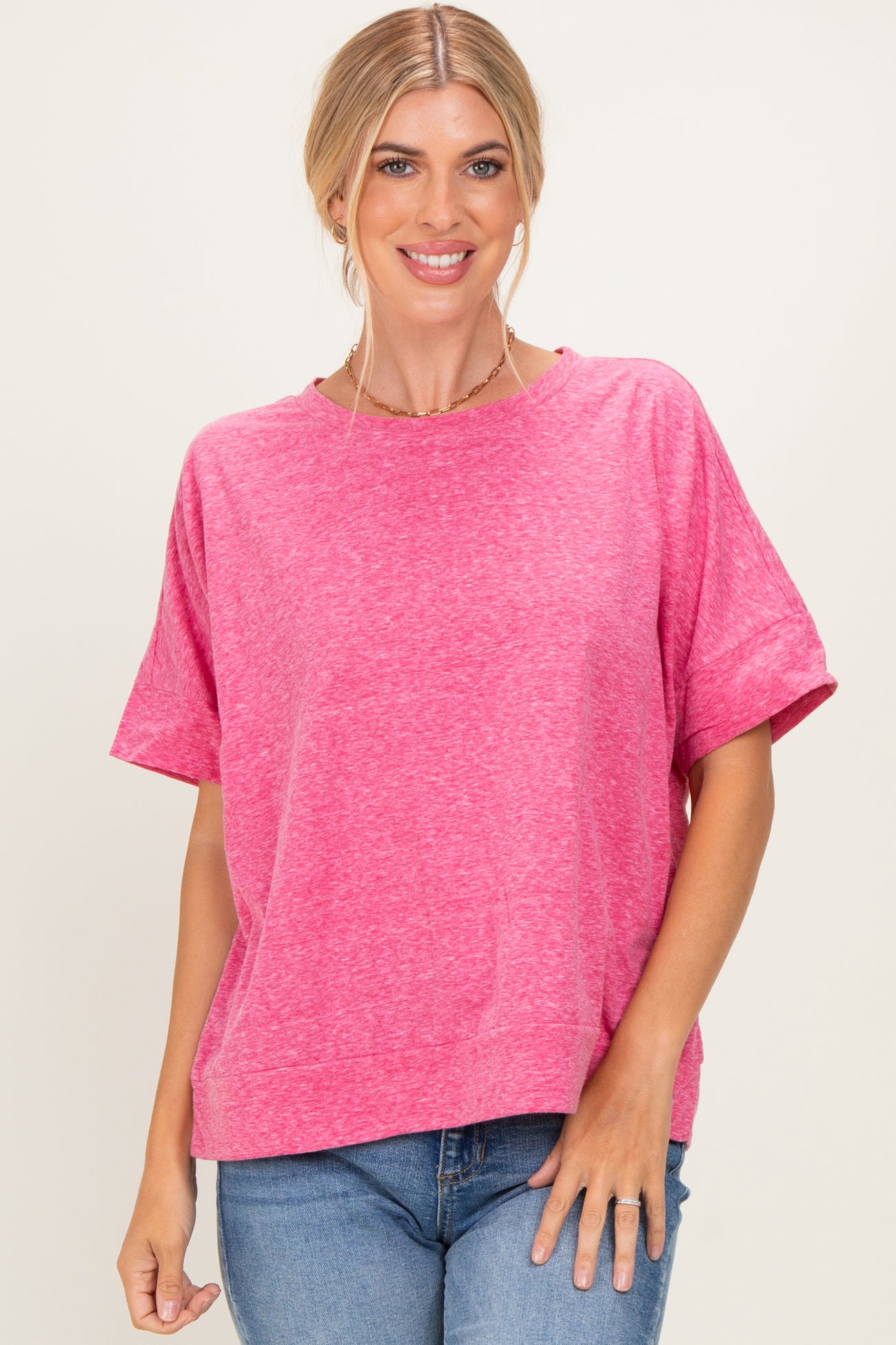 woman wearing a bright pink short sleeve top with a relaxed fit and round neckline, styled with blue jeans