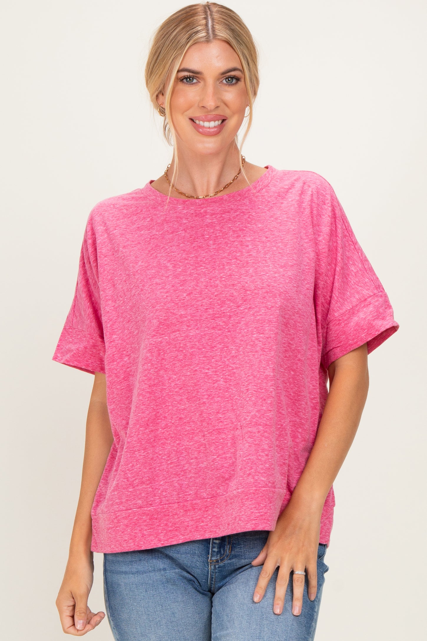woman wearing a bright pink short sleeve top with a relaxed fit and round neckline, styled with blue jeans