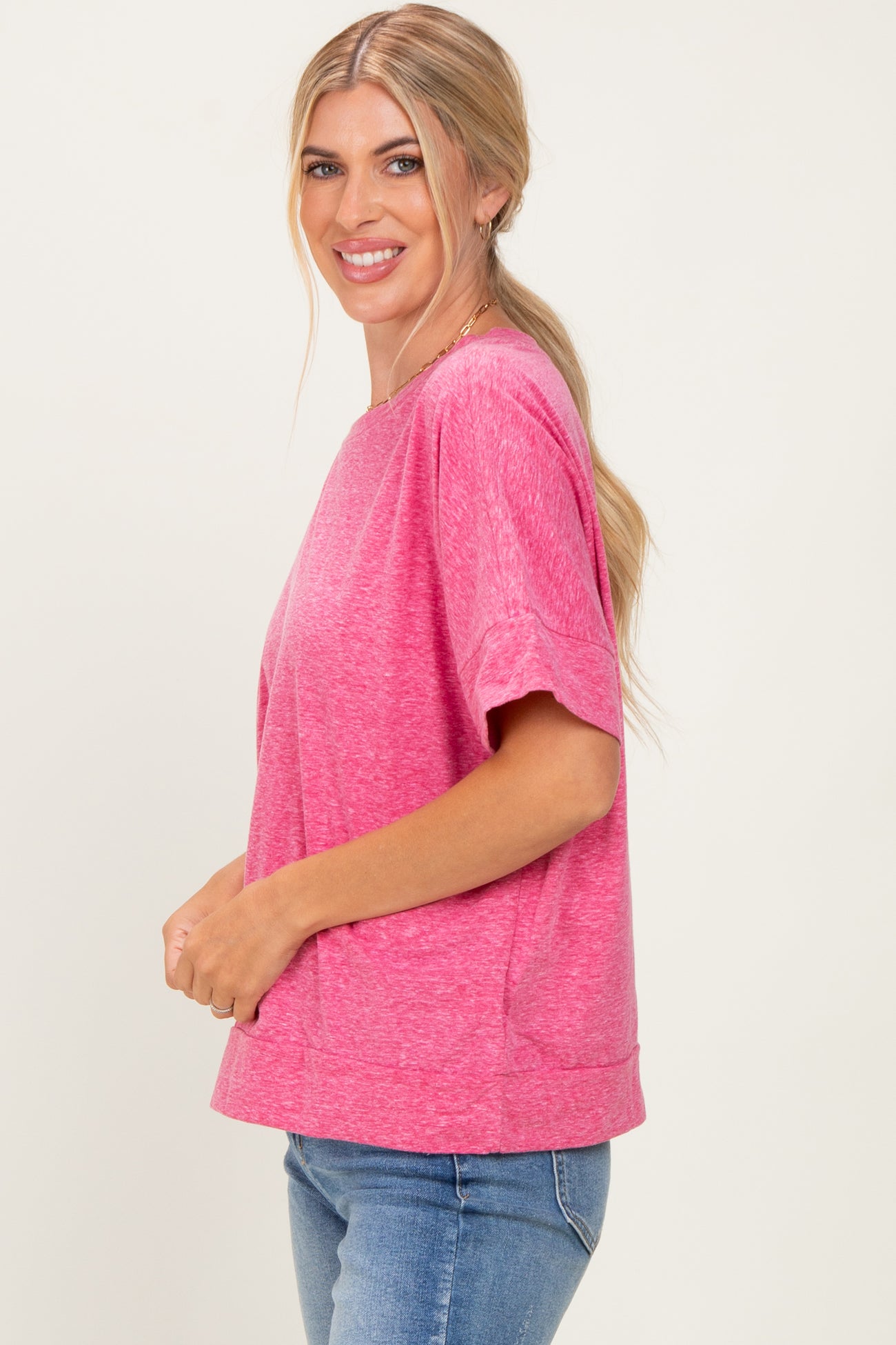woman wearing a bright pink short sleeve casual top paired with blue jeans