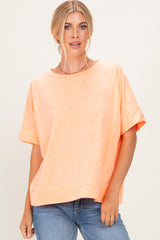 woman wearing an oversized light orange t-shirt with short sleeves and a relaxed fit, paired with blue jeans