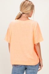 woman wearing an orange oversized t-shirt, viewed from the back, paired with light blue jeans