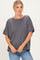 woman wearing a dark gray oversized t-shirt with short sleeves and a relaxed fit, paired with blue jeans