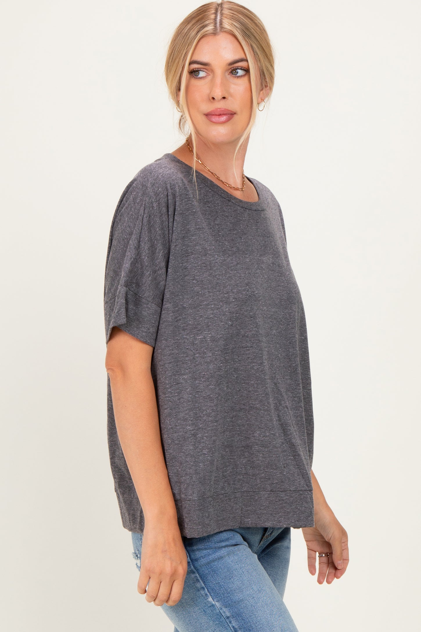 woman wearing a gray short sleeve loose fit top with a round neckline and side slits