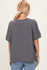 woman wearing a charcoal gray short sleeve top, showing a relaxed fit and back details, paired with blue jeans