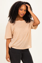 woman wearing a light tan oversized short sleeve top with a relaxed fit and styled curly hair, posing confidently
