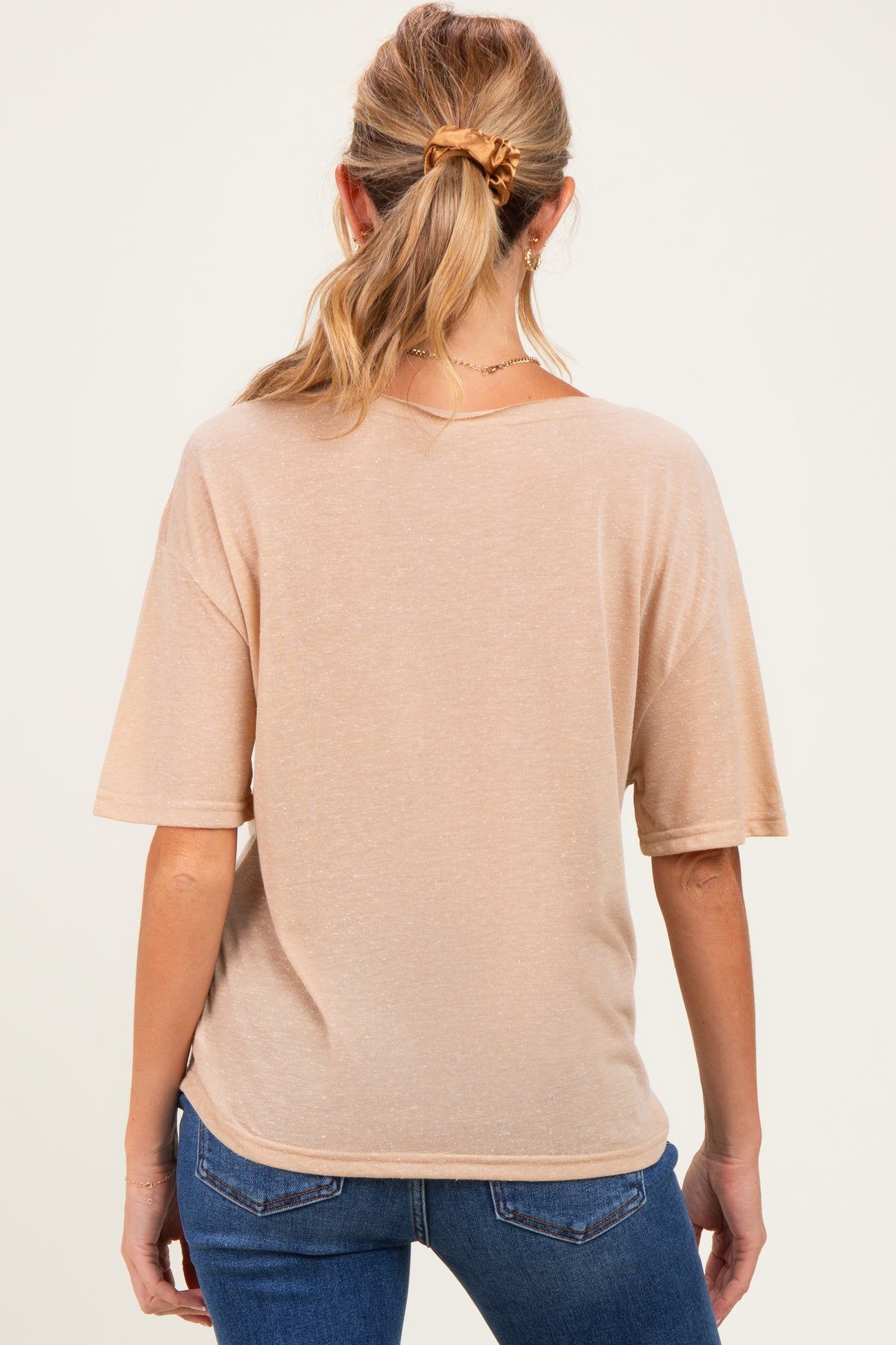 woman wearing a light beige maternity top with short dolman sleeves, showing a relaxed fit from the back