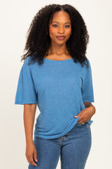 woman wearing a blue oversized t-shirt paired with jeans, smiling and posing casually