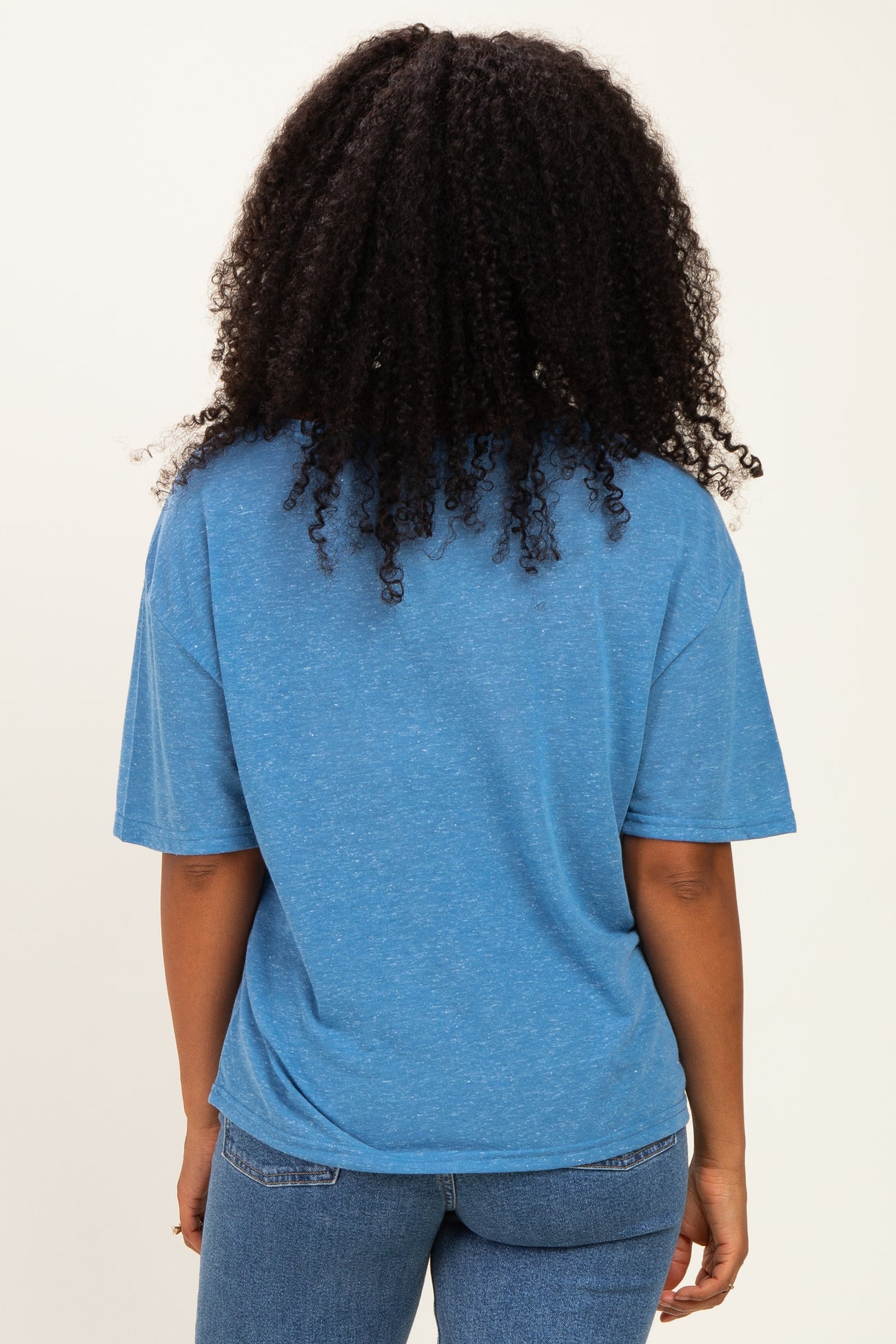 woman wearing a blue oversized short sleeve t-shirt and blue jeans, viewed from the back