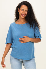 woman wearing a blue maternity top with short sleeves and holding her baby bump